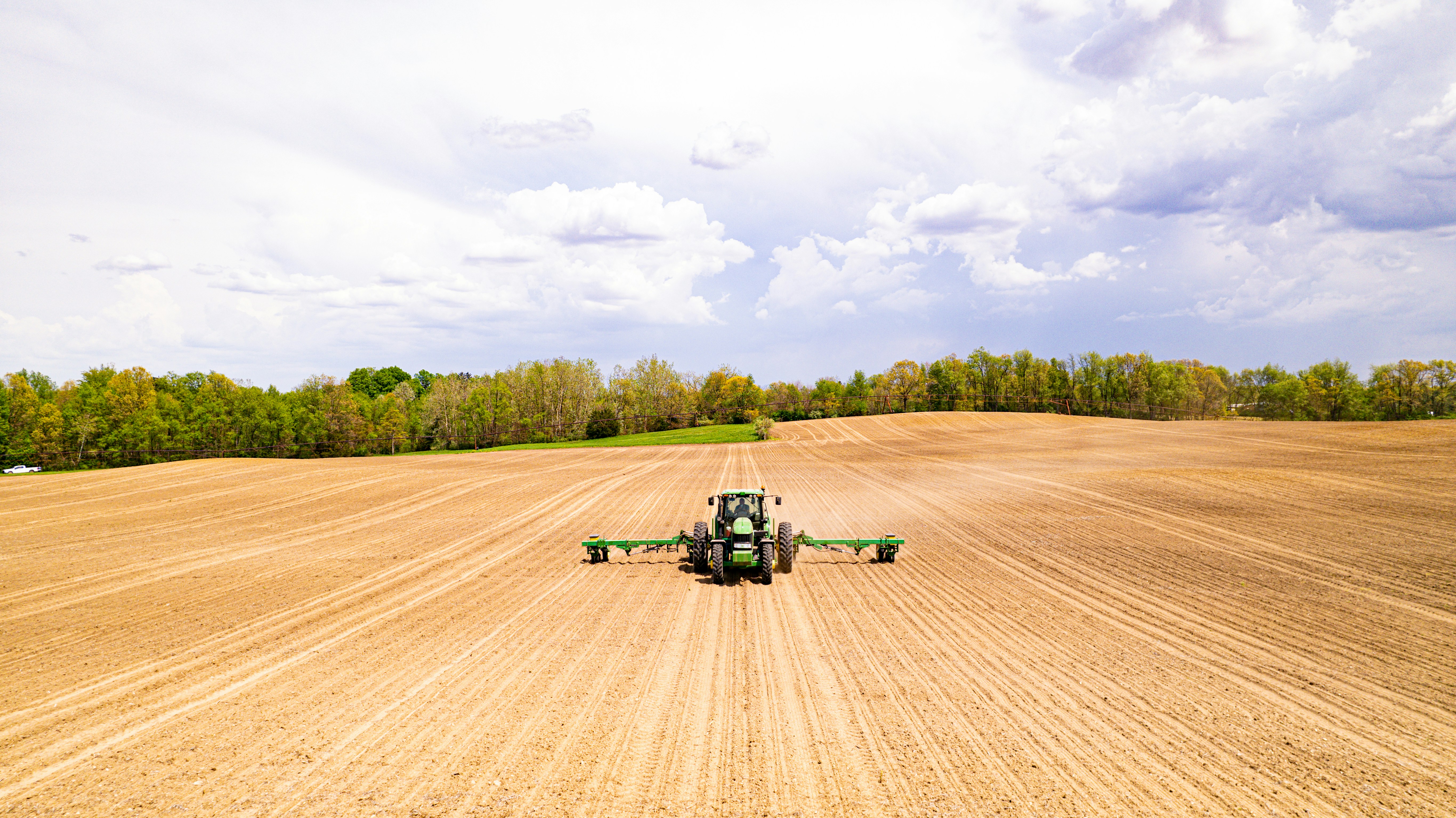 Aerial view of tractor with agricultural equipment in a plowed field